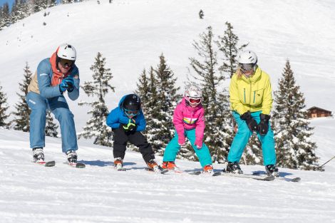 Eltern lernen Ihren Kindern das Skifahren auf der Skipiste in Unken