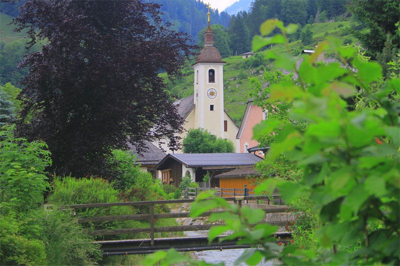 Die Kirche von Weissbach mit den Bergen im Hintergrund